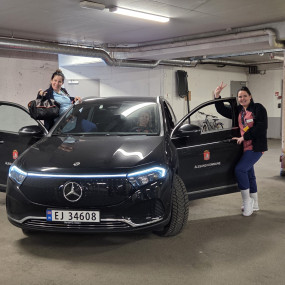 To personer står ved en bil i en garasje