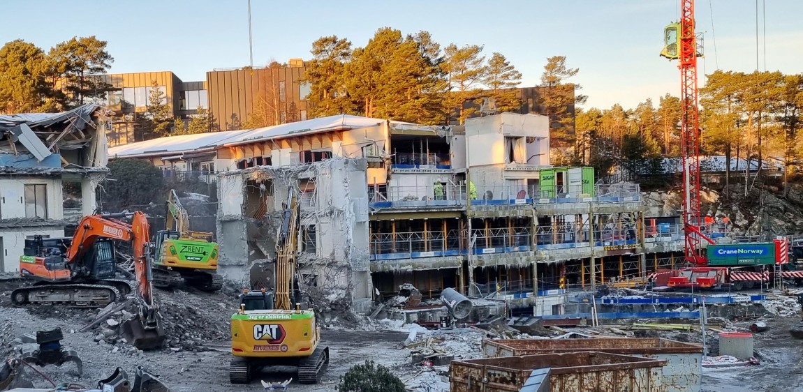 Bilder viser bygninger som rives med elektrisk mobilkran og gravemaskiner.