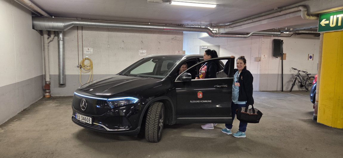 To personer står ved en bil i en garasje